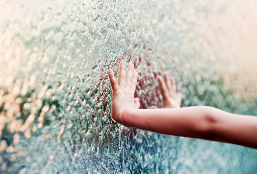 child's hand touching running water