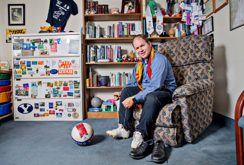 Mikle South laces up his soccer cleats in his colorful office
