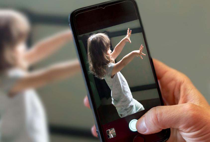Close up of phone with Cognoa app in use, apparently taking video or a photo of a child exhibiting stimming behaviors or repetitive motions.