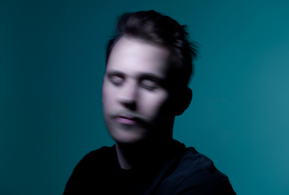 Young man partly in shadow in blurred motion on dark green background.