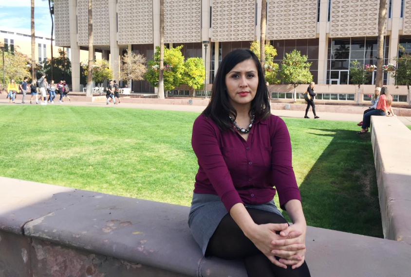 Vanessa Ramirez sits on a ledge at a college campus