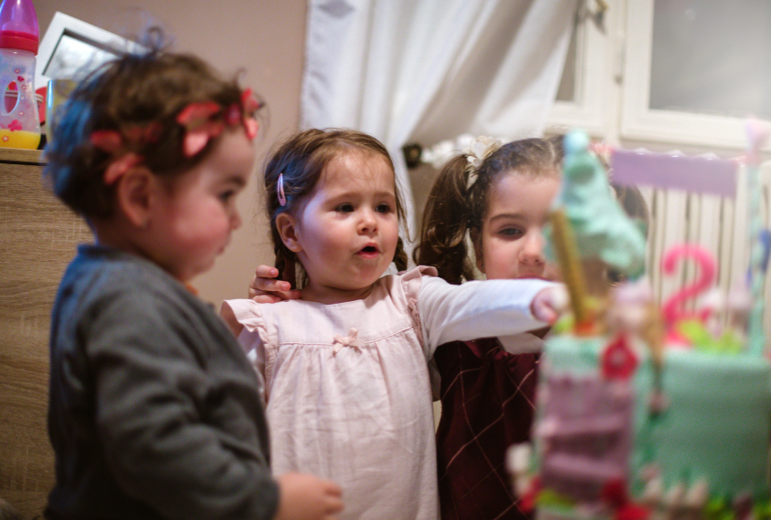 Three toddlers looking at a stack of presents.