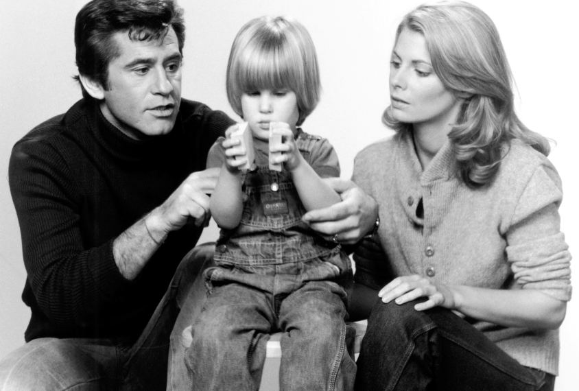 mother and father watching a child focus on toys. 