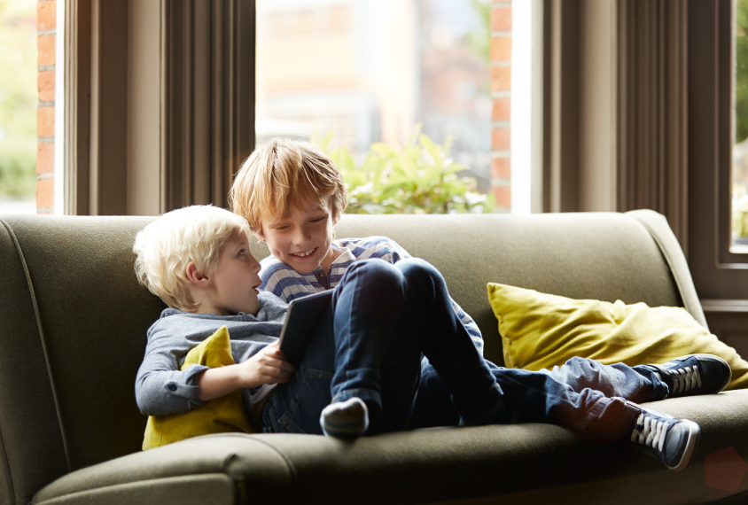 Boy and toddler sitting on sofa.