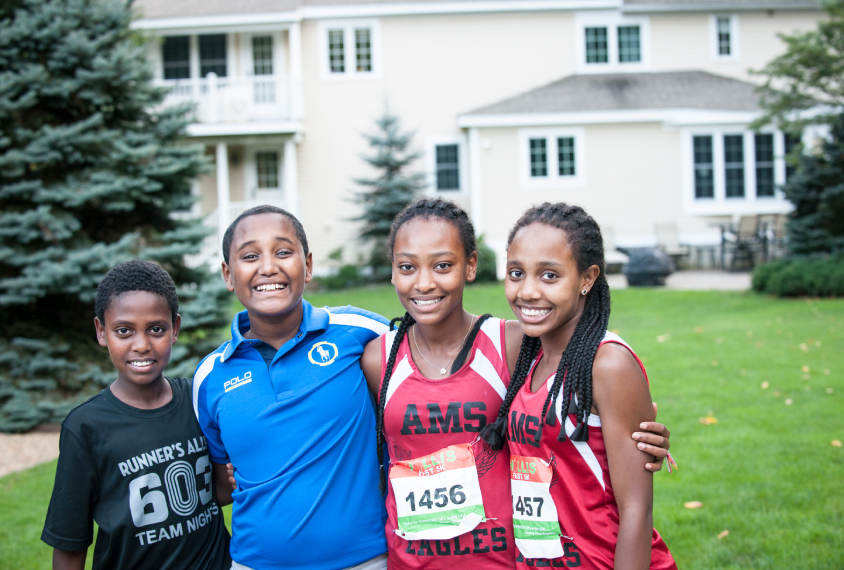 Photo: A portrait of Asaminew with his three siblings. They're standing in the backyard of a large house.