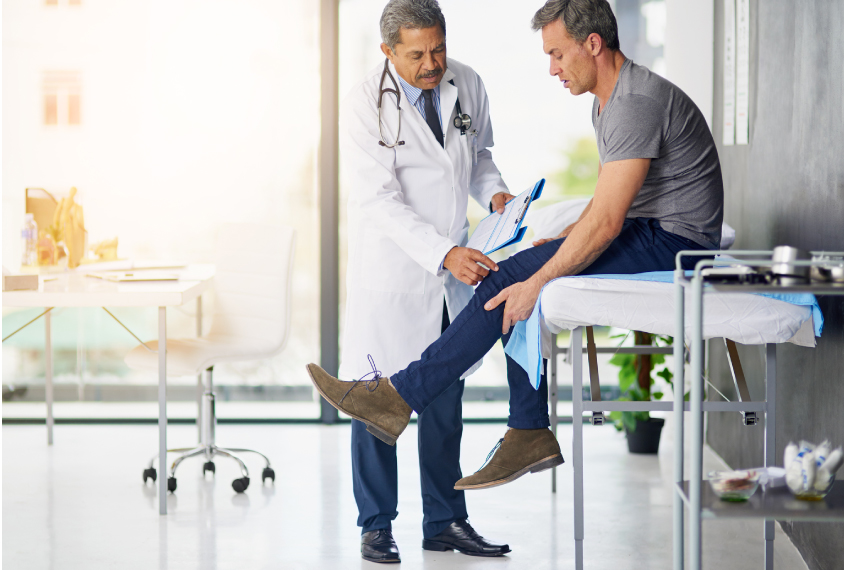 doctor touching male patient's knee