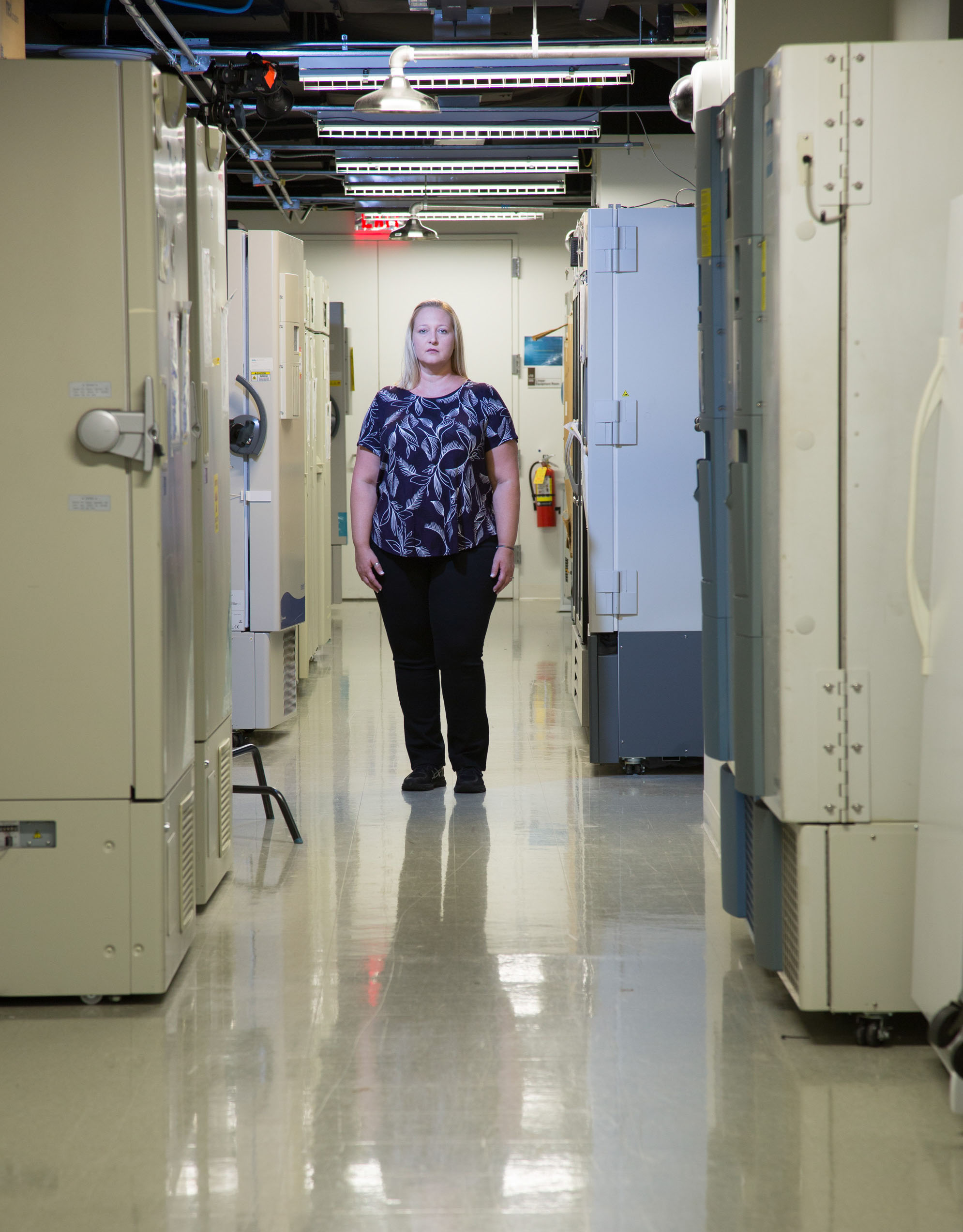 Photo: Leslie Bolen, a blond woman, stands between medical equipment. She's wearing a black and white patterned top and black pants.