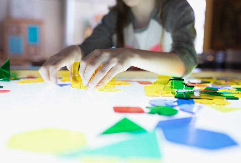 child working on colorful puzzle on lightbox