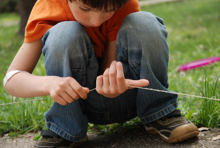 Boy examining string in the grass