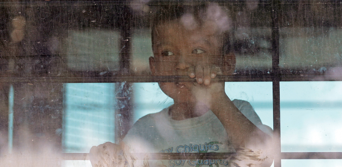A lone child looks out from a U.S. Border Patrol bus leaving as protesters block the street outside the U.S. Border Patrol Central Processing Center Saturday, June 23, 2018, in McAllen, Texas.