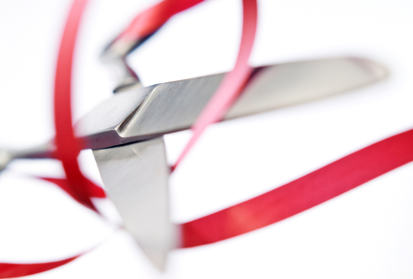 silver scissors float on white, about to cut a red ribbon.