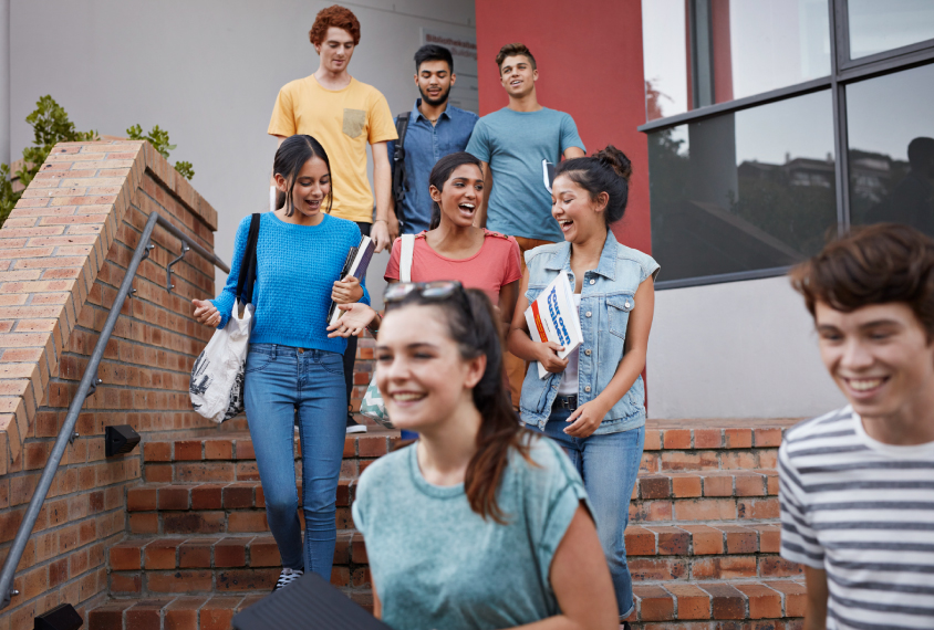 A group of high school kids walking down a set of stairs outside a building.