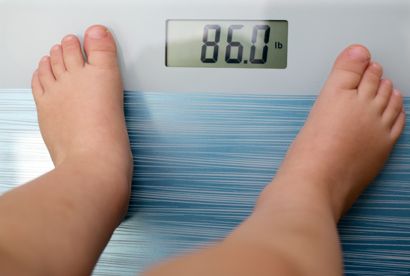 Feet of a child on a scale, weighing in at 86 pounds.