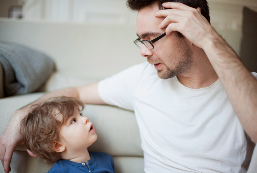 Father and son talking on the couch.