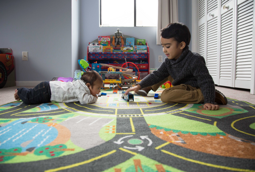 Siblings, a baby and a toddler, play together at home.