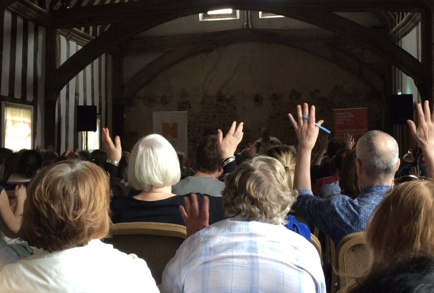 seated crowd using silent applause, 'flappause' to show appreciation for a speaker