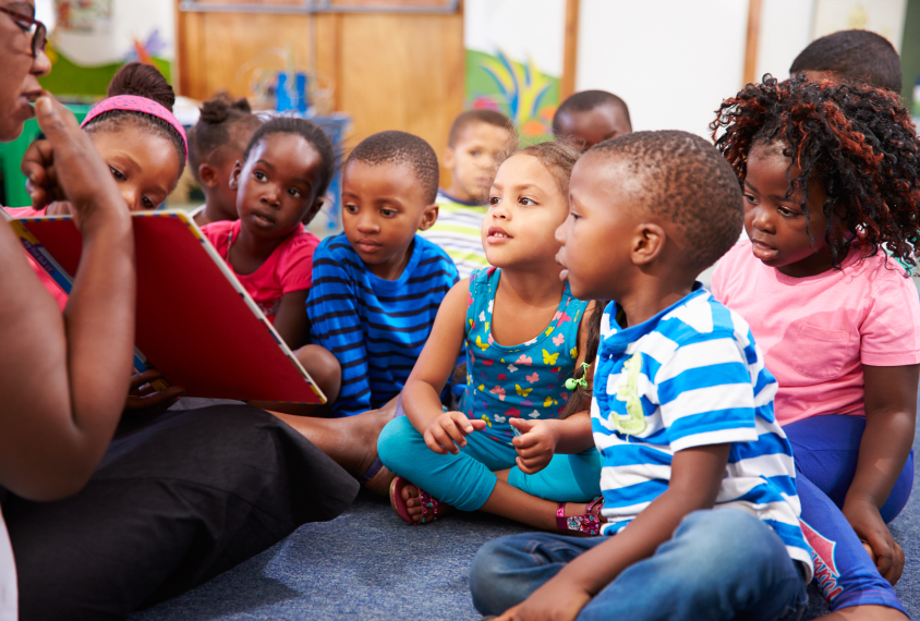 Teacher reading a book with a class of children