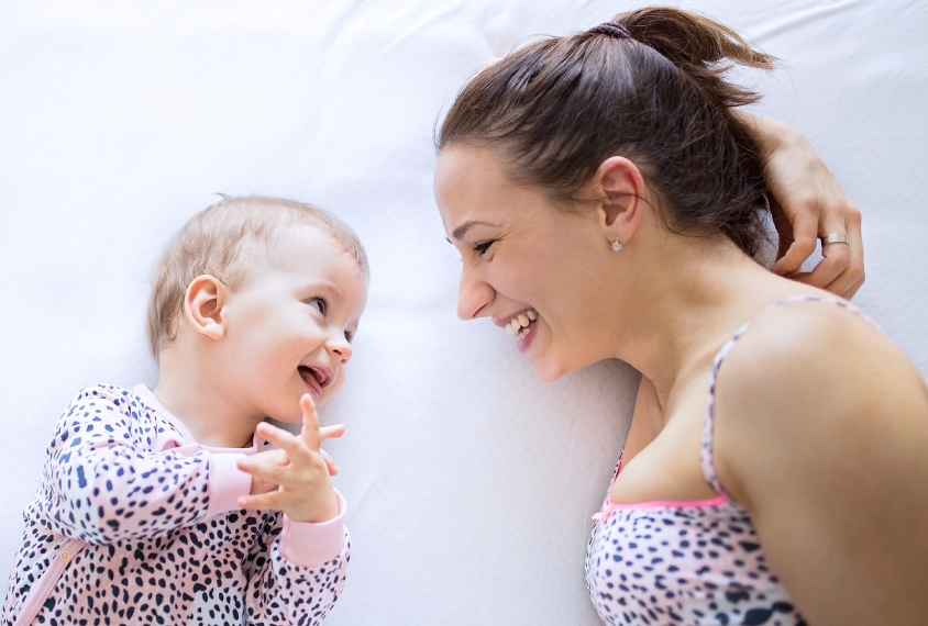 mother talking to a baby on bed