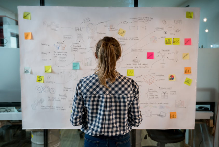 woman standing alone confronts a complex chart in the workplace