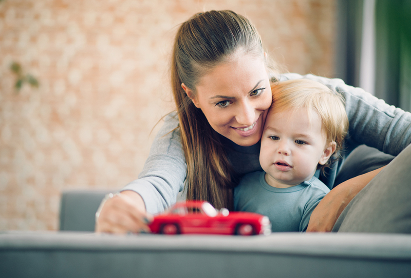 Mom and toddler looking at a red toy car