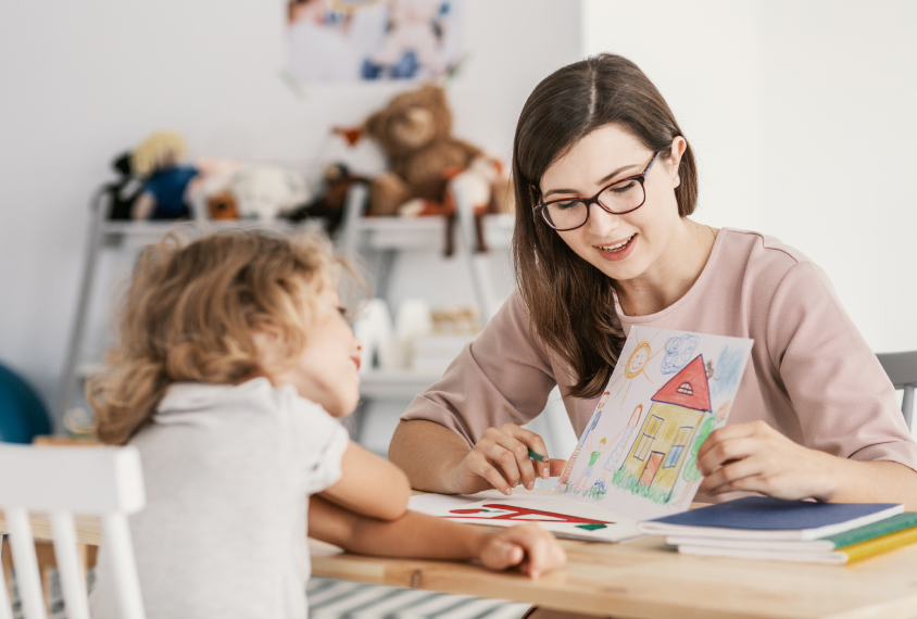 therapist in session with child, showing picture cards.