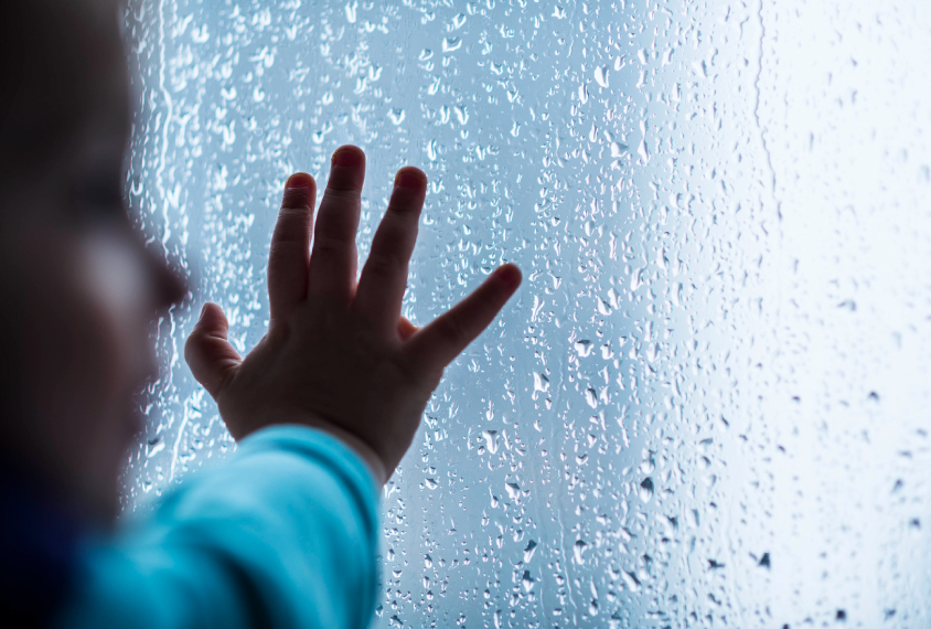 Close-up of child's hand on wet window