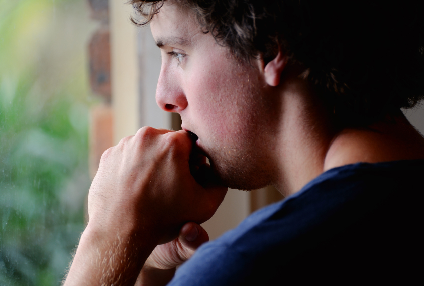 Young man looks out of window, anxiously