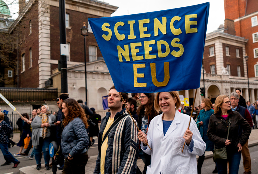 A scientist protesting Brexit holds a 'Science needs EU' banner on a march in London