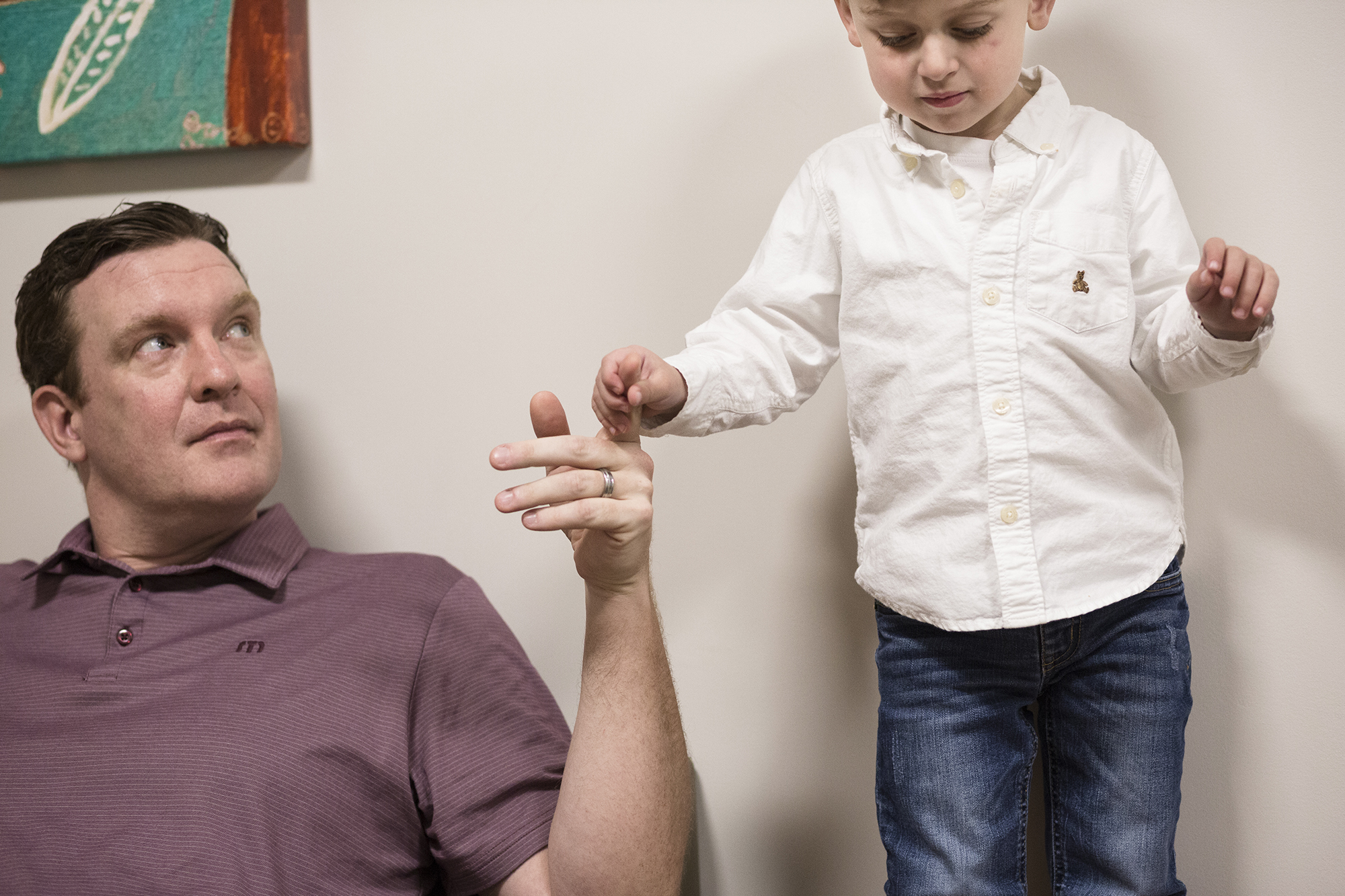 Photo: Owen stands up next to his father, grasping his hand.