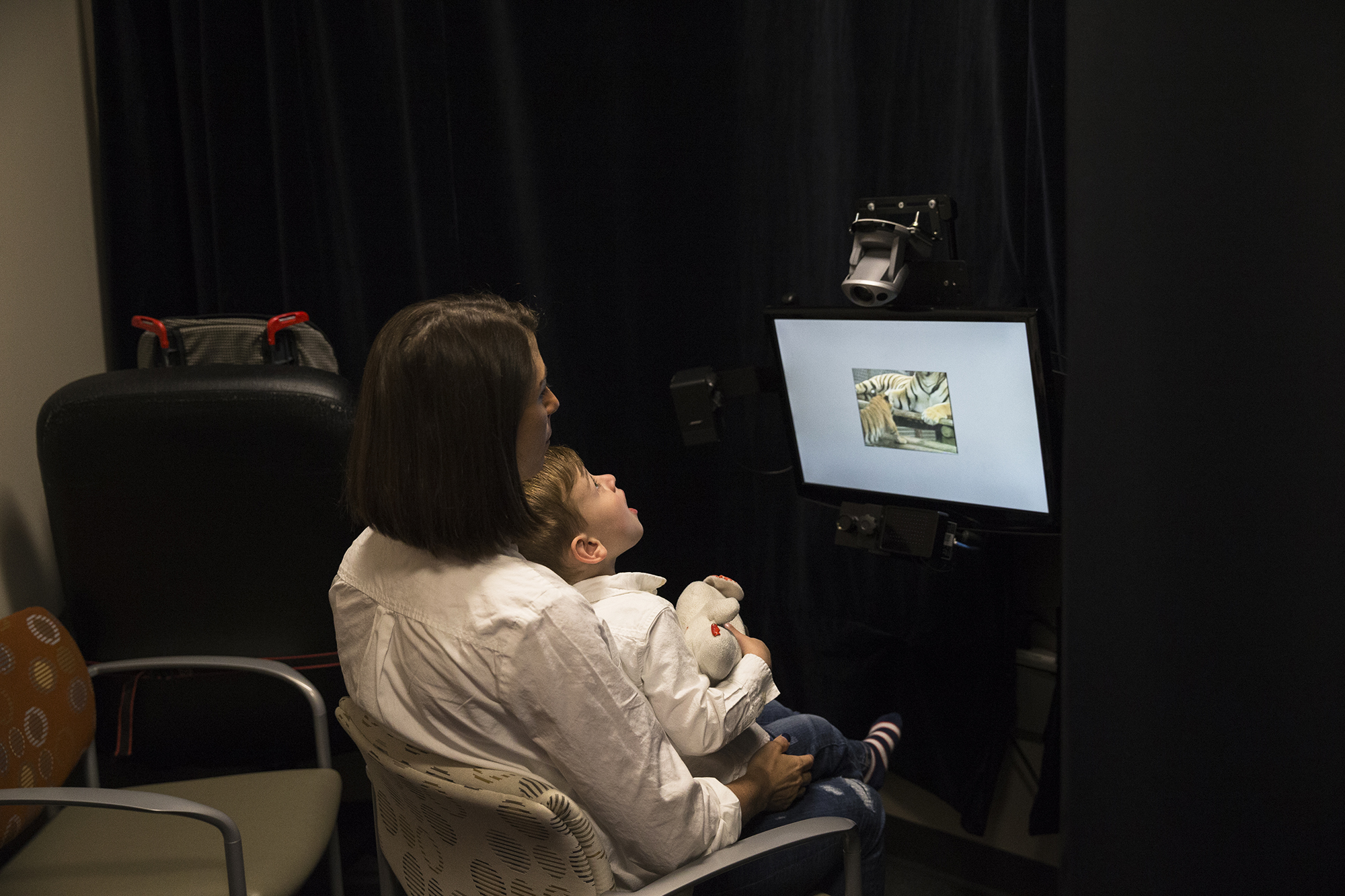 Photo: Owen sits on his mother's lap, looking at a screen.