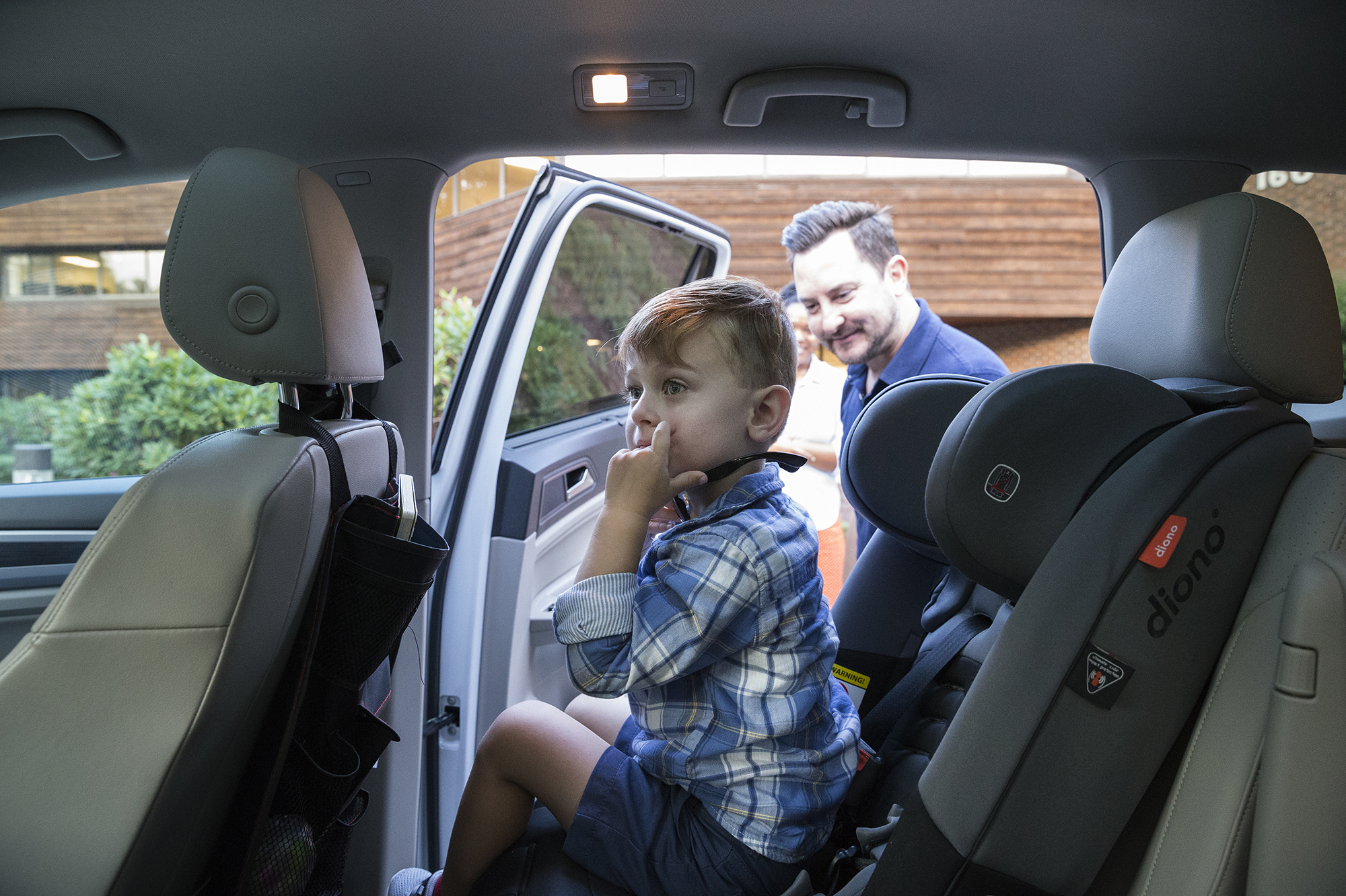 Photo: Owen is unbuckled from his car seat, sitting in the car and looking around. His father stands outside the car, waiting for Owen to climb out.