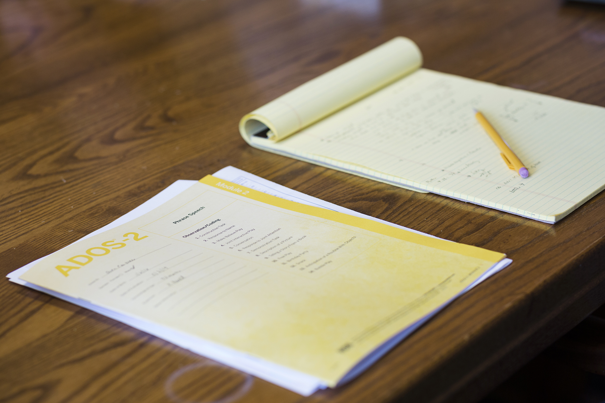 Photo: A workbook and a legal pad lie side by side on a wooden table. A yellow mechanical pencil lays on the legal pad.