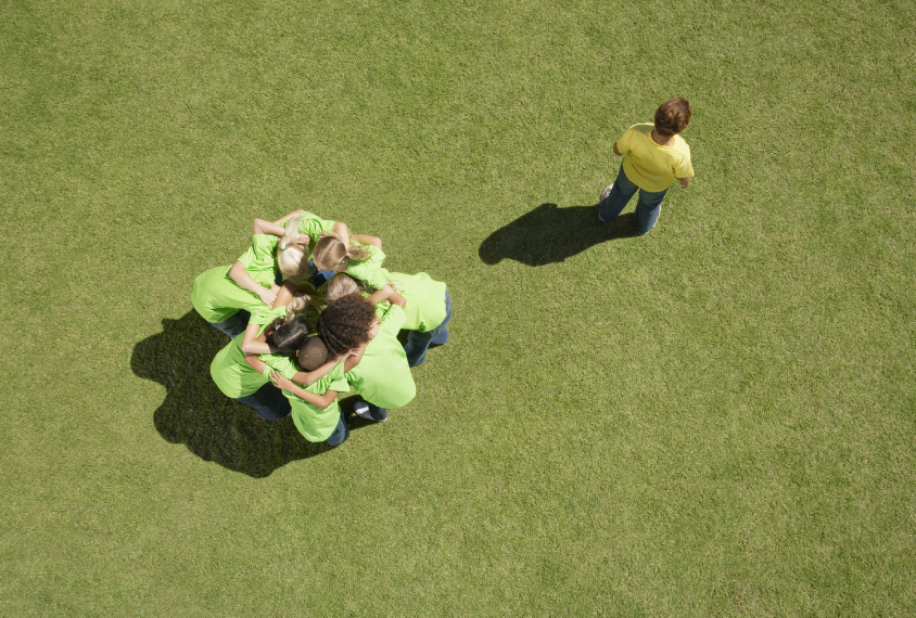 boy alone outside of group on playing field