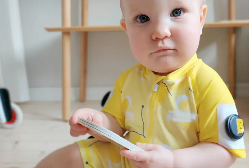 A baby in a yellow jumper that has movement tracking sensors