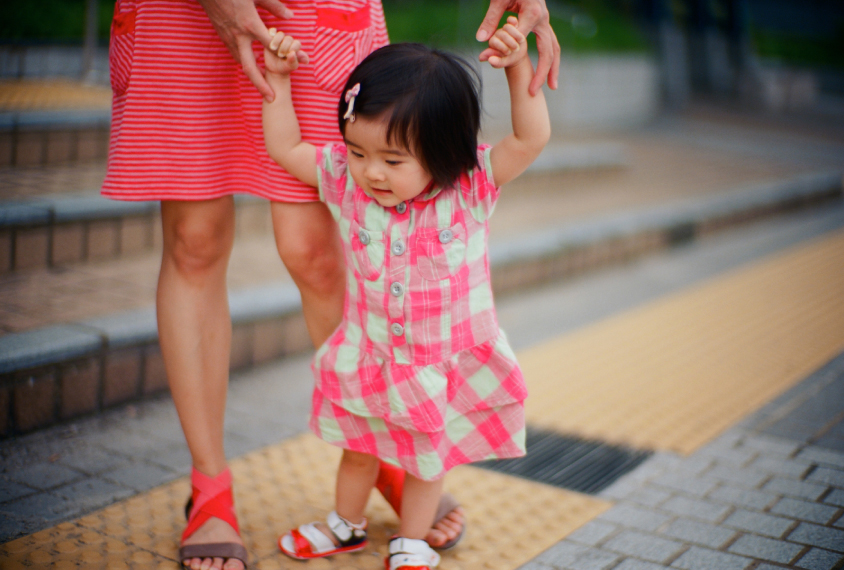 Toddler is balancing with help from mom