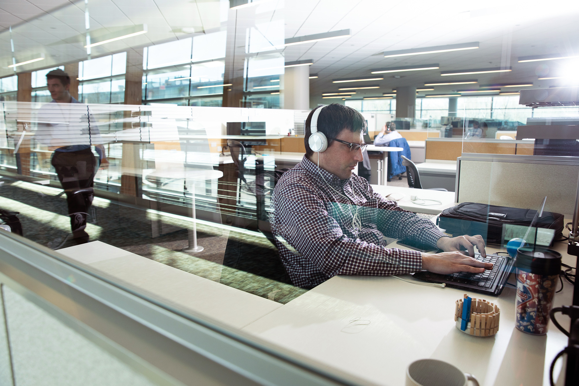 Photo: A white man wearing headphones works on a laptop.