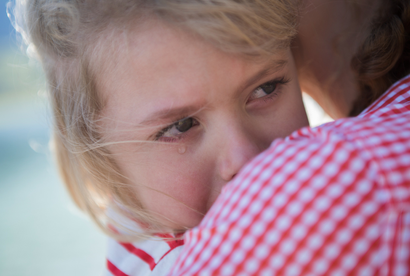 Young girl crying into mother's shoulder