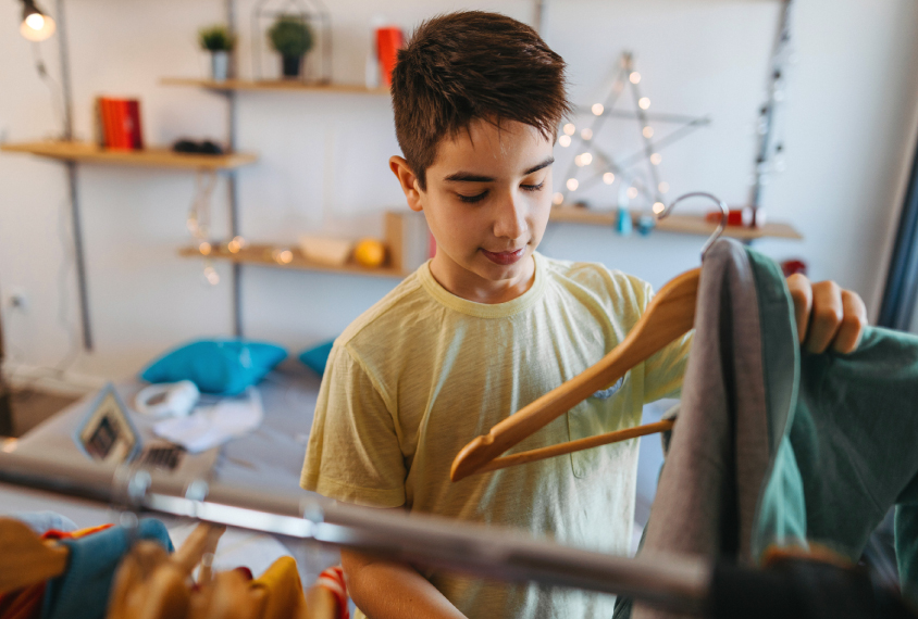 Young teen boy is getting dressed, choosing clothes.