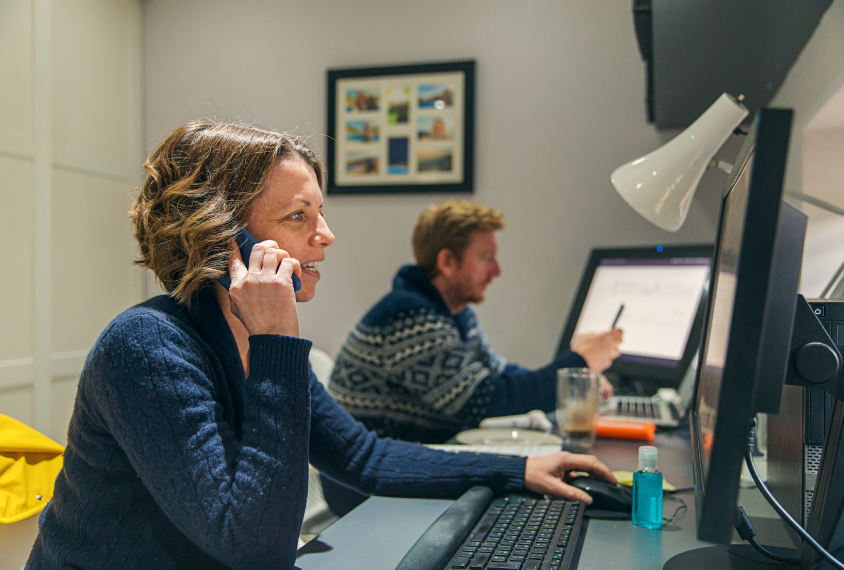 Researcher talking on phone and working on computer at home.