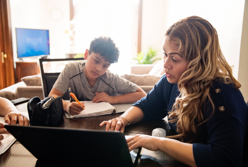 Mom at home with two kids trying to help them with online work.