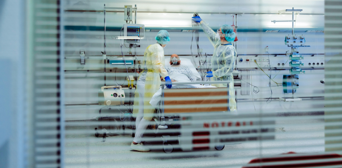 patient in hospital on ventilator, seen through a window.