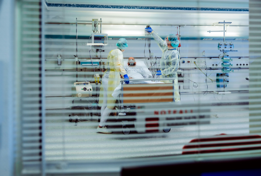 patient in hospital on ventilator, seen through a window.