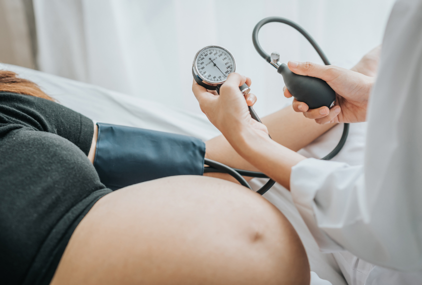 Doctor checking pregnant woman's blood pressure.