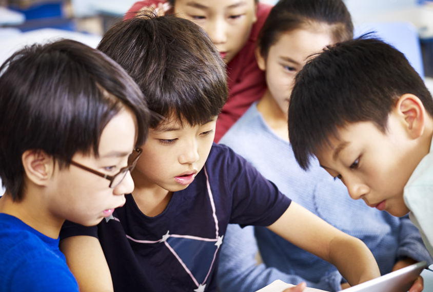 Small group of Chinese students looking at tablet together.