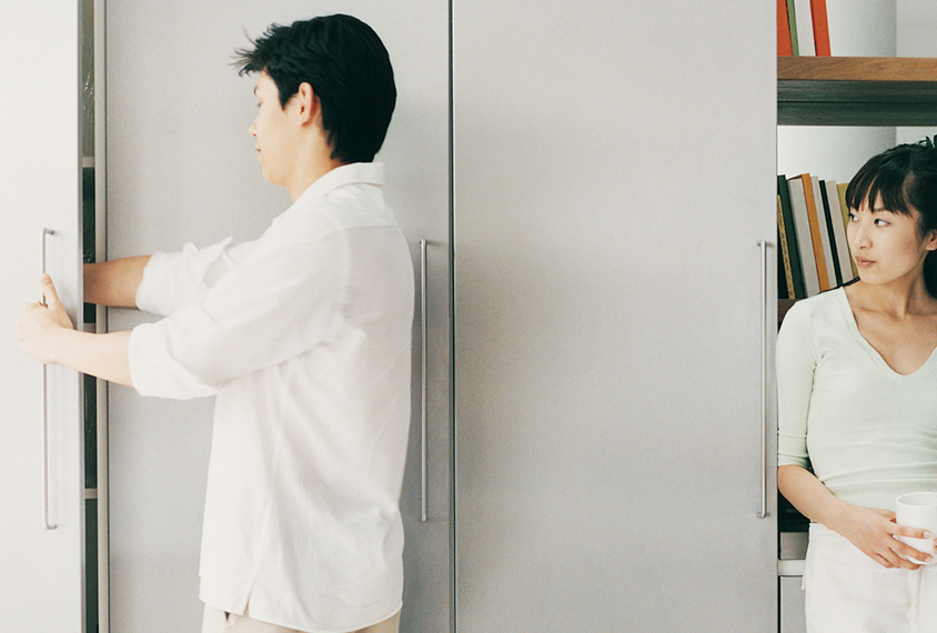 Man reaches into cabinet while a woman looks on