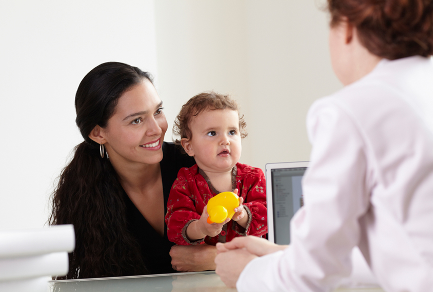 Mother and child with doctor and computer.