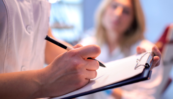 Doctor or clinician makes notes about patient during diagnosis.