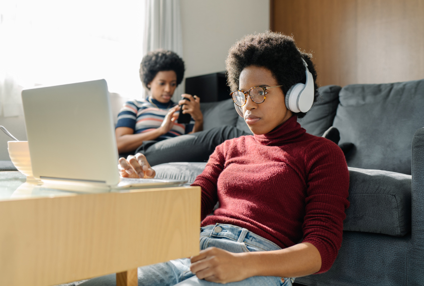 Twin sisters spending their time using laptop and smart phone at home