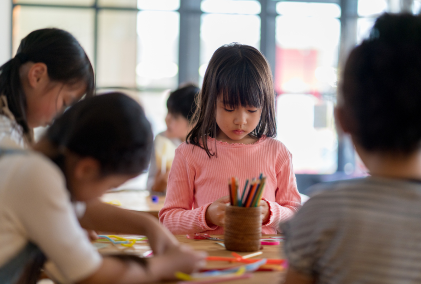 Young girl in kindergarten classroom, concentrating.