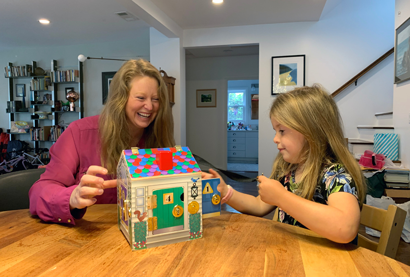 Mother and child during remote diagnosis, with learning toys, in their living room.